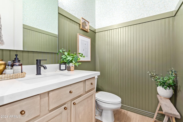 bathroom featuring hardwood / wood-style floors, wood walls, vanity, and toilet