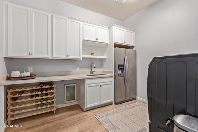 kitchen with white cabinets, stainless steel refrigerator with ice dispenser, light hardwood / wood-style flooring, and sink