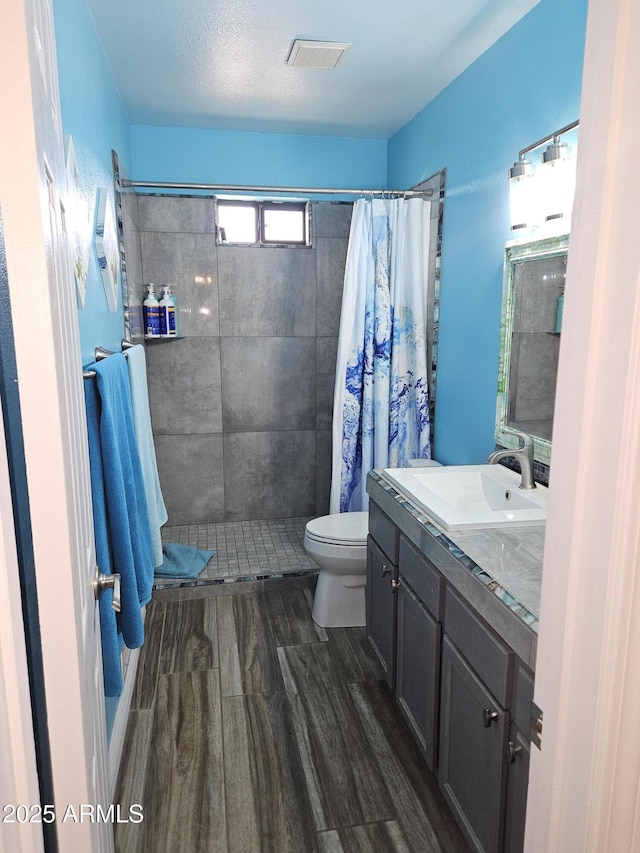 bathroom featuring toilet, wood-type flooring, vanity, and walk in shower