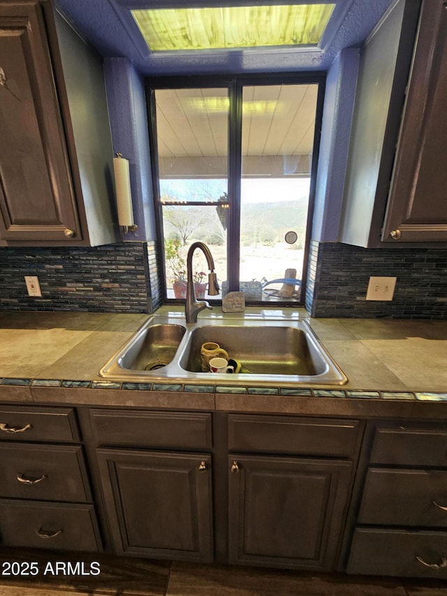 kitchen featuring sink, backsplash, and dark brown cabinets