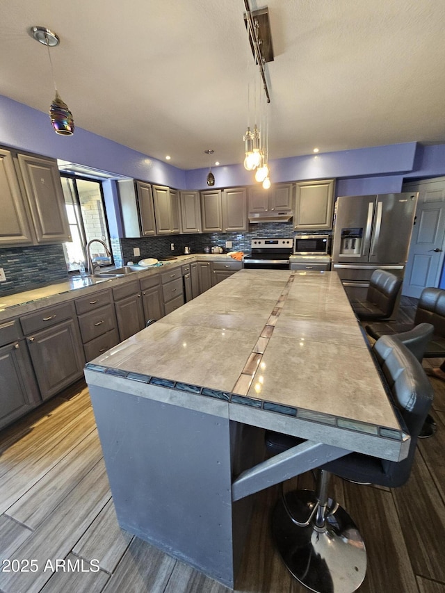 kitchen featuring sink, a center island, hanging light fixtures, and appliances with stainless steel finishes