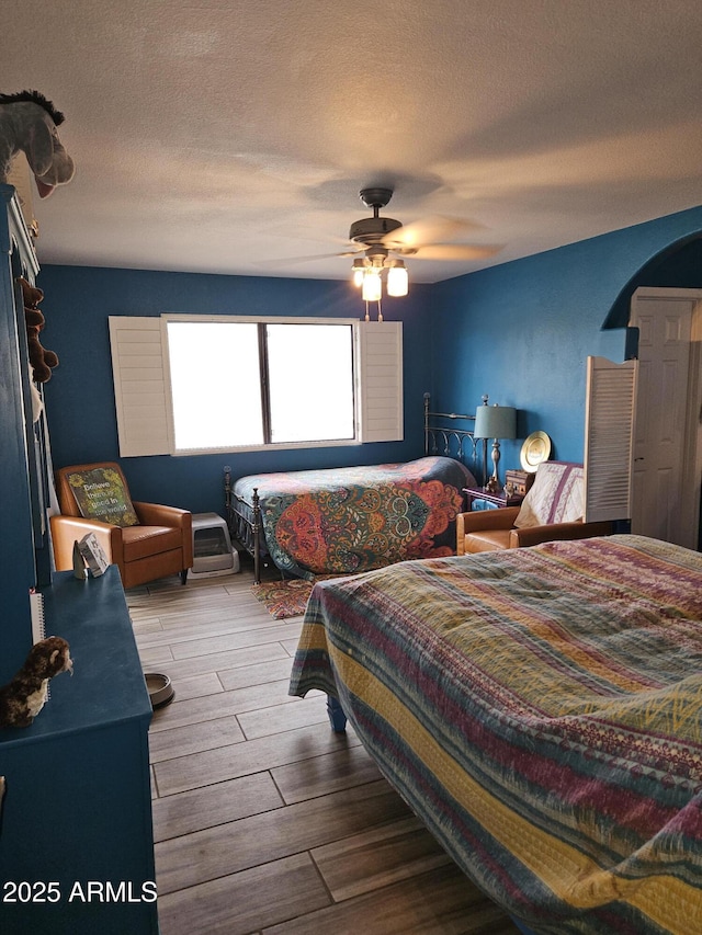 bedroom featuring ceiling fan, a textured ceiling, and wood-type flooring