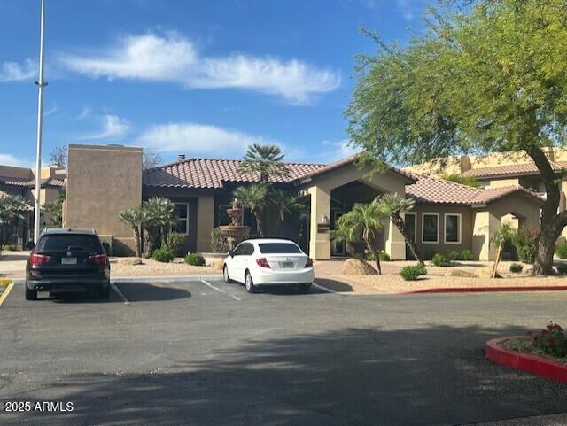 mediterranean / spanish-style home featuring a tile roof, uncovered parking, and stucco siding