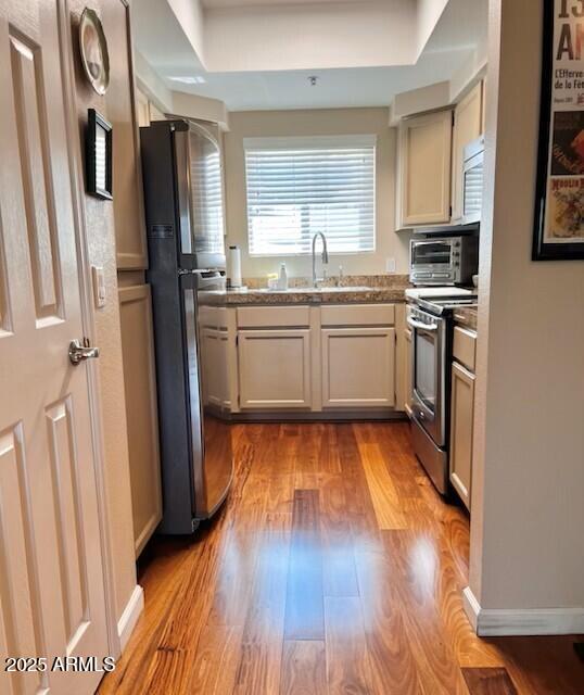 kitchen with stainless steel appliances, a sink, and wood finished floors