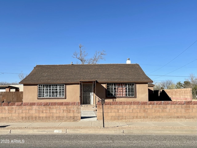 single story home with roof with shingles, a fenced front yard, and stucco siding