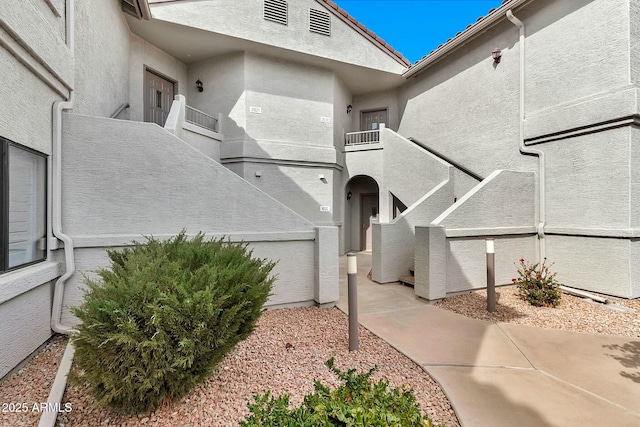 view of exterior entry with stucco siding and a balcony