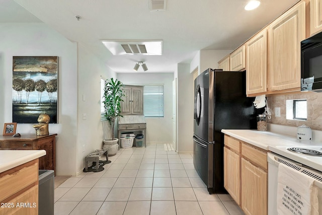 kitchen featuring visible vents, black microwave, light brown cabinetry, light tile patterned floors, and decorative backsplash