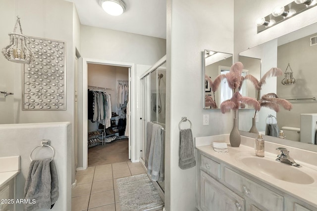 full bathroom featuring a walk in closet, vanity, a shower stall, and tile patterned flooring