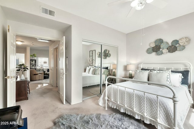 carpeted bedroom featuring visible vents, a closet, and a ceiling fan