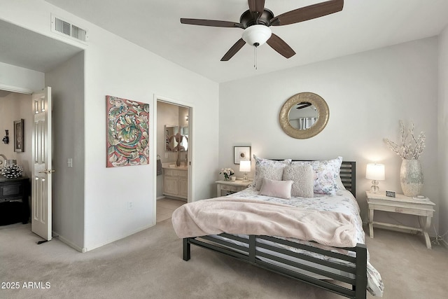 bedroom with visible vents, baseboards, light colored carpet, and ensuite bath