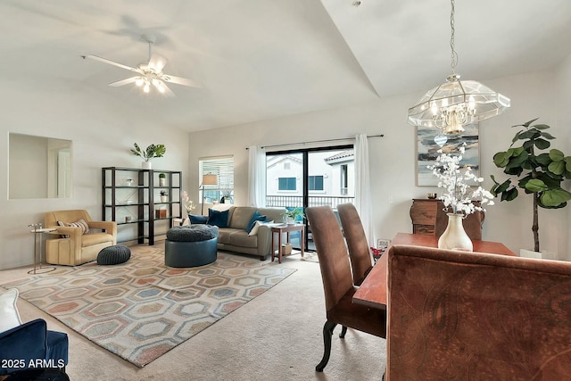 carpeted living area featuring ceiling fan with notable chandelier and high vaulted ceiling