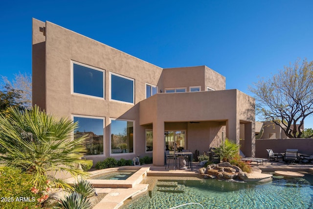 back of property with a patio area and a pool with hot tub