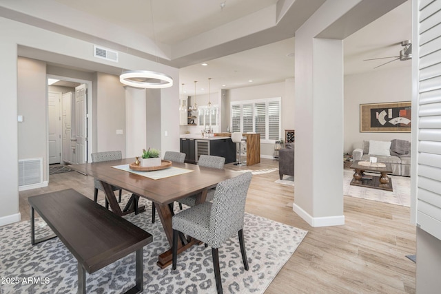 dining space featuring light wood-type flooring and ceiling fan with notable chandelier