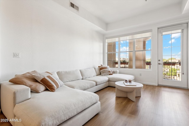 living area featuring visible vents, baseboards, and wood finished floors