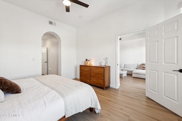bedroom featuring arched walkways, ceiling fan, light wood-style flooring, and visible vents