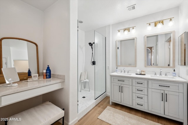 full bath featuring visible vents, a shower stall, a sink, and wood finished floors
