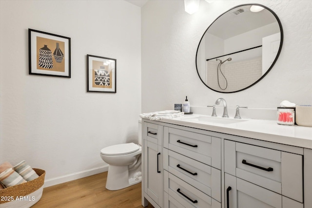 bathroom featuring visible vents, wood finished floors, baseboards, vanity, and toilet