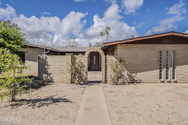 view of front of house featuring brick siding, fence, and a gate