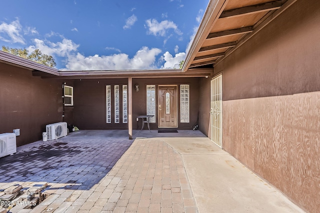 property entrance featuring ac unit, stucco siding, and a patio