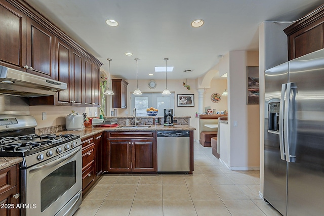 kitchen featuring a sink, under cabinet range hood, appliances with stainless steel finishes, a peninsula, and light tile patterned floors