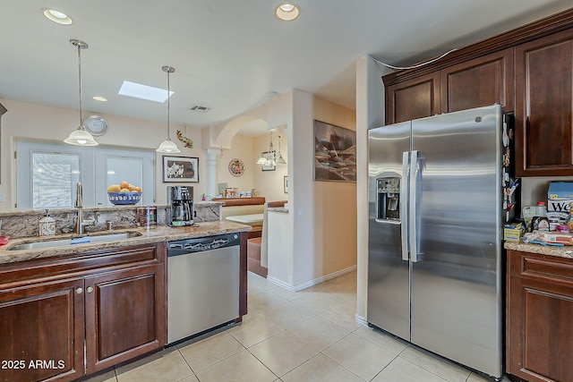 kitchen with light stone counters, visible vents, arched walkways, a sink, and stainless steel appliances