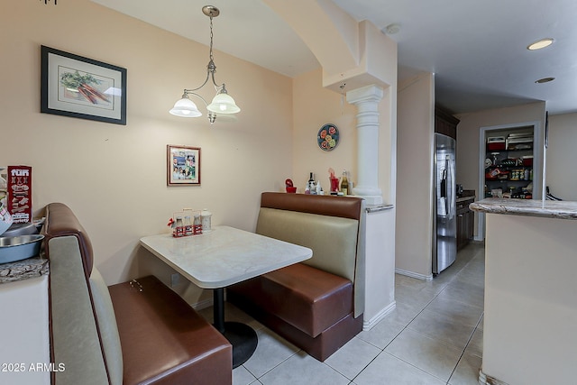 dining area featuring light tile patterned flooring, arched walkways, and baseboards