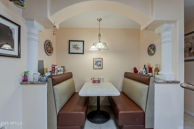 dining room featuring tile patterned floors, decorative columns, baseboards, and arched walkways