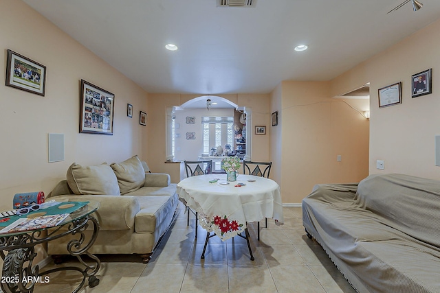 living room featuring recessed lighting, light tile patterned flooring, visible vents, and arched walkways