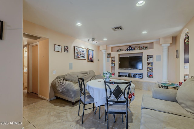 living room featuring built in features, light tile patterned flooring, visible vents, and ornate columns