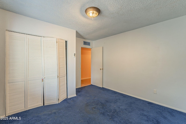 unfurnished bedroom featuring baseboards, visible vents, a closet, a textured ceiling, and dark carpet