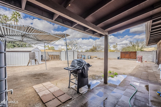 view of patio with a storage unit, an outbuilding, area for grilling, and a fenced backyard