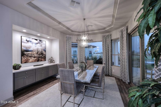 dining area featuring a chandelier, dark hardwood / wood-style flooring, and a raised ceiling