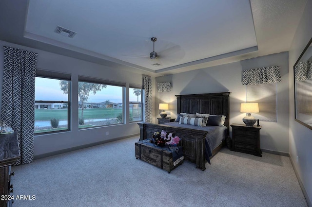 carpeted bedroom featuring ceiling fan and a raised ceiling