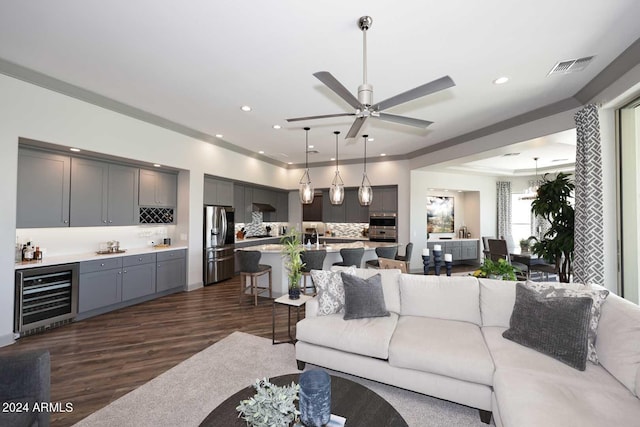 living room with ceiling fan, beverage cooler, dark hardwood / wood-style floors, and ornamental molding