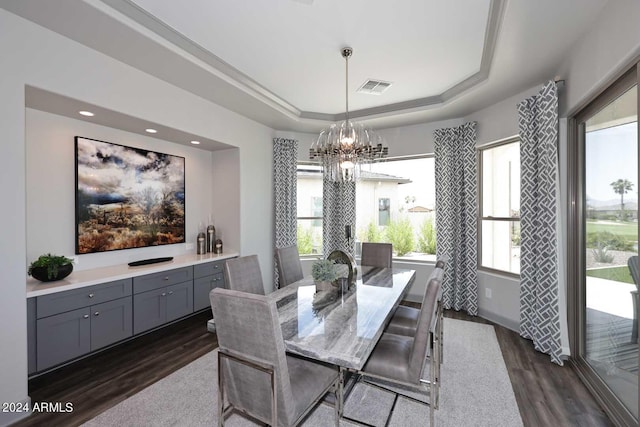 dining space with a raised ceiling, dark wood-type flooring, and a notable chandelier