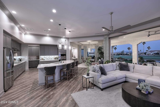 living room featuring hardwood / wood-style floors, ceiling fan, and sink