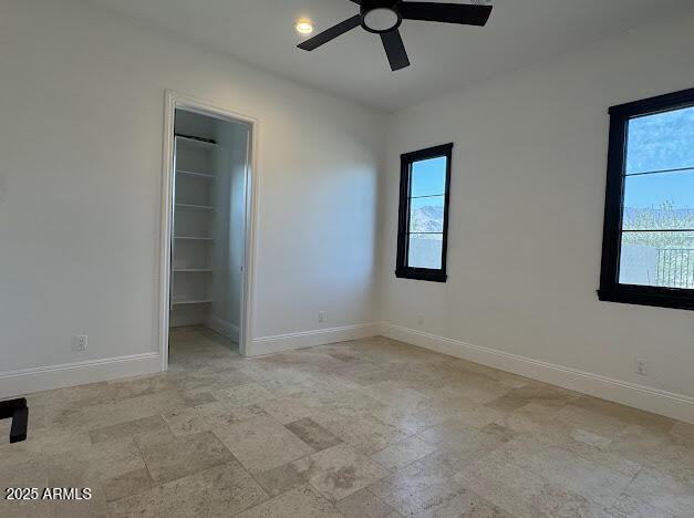 unfurnished bedroom with a closet, a spacious closet, and ceiling fan