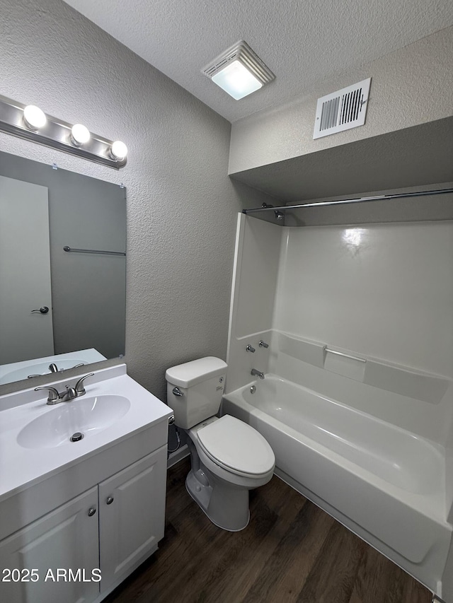 3749 W Gelding Dr, Phoenix, AZ 85053 - bathroom with wood finished floors, a textured wall, vanity, toilet, and shower / bathtub combination
