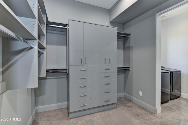 walk in closet with washing machine and dryer and light tile patterned floors