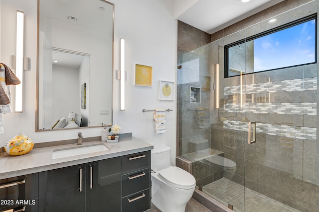 bathroom featuring vanity, toilet, and a shower with door