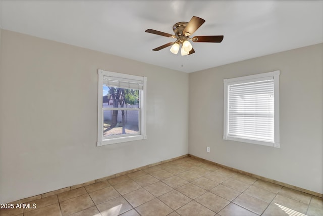 empty room with ceiling fan, baseboards, and light tile patterned floors