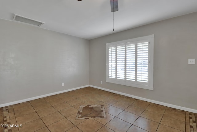 tiled spare room featuring baseboards, visible vents, ceiling fan, and attic access