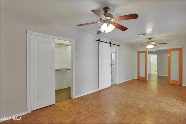 unfurnished bedroom featuring a walk in closet, visible vents, baseboards, and a barn door