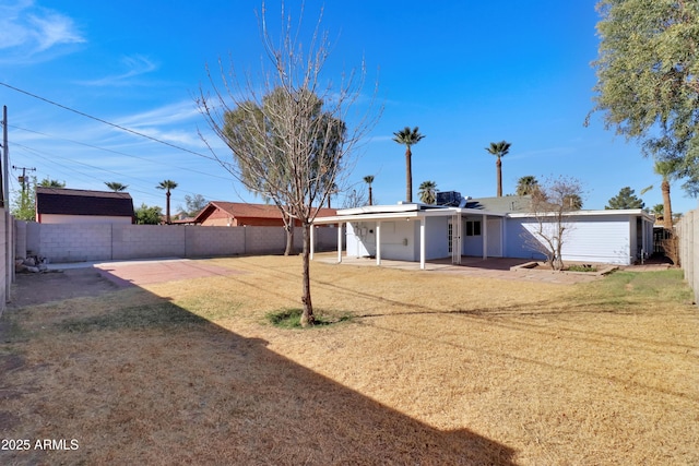 rear view of property featuring a patio, a yard, and a fenced backyard