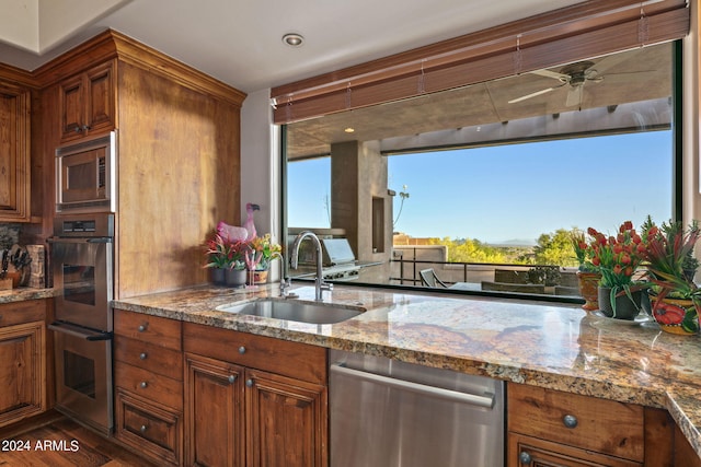 kitchen featuring light stone countertops, sink, ceiling fan, stainless steel appliances, and dark hardwood / wood-style flooring