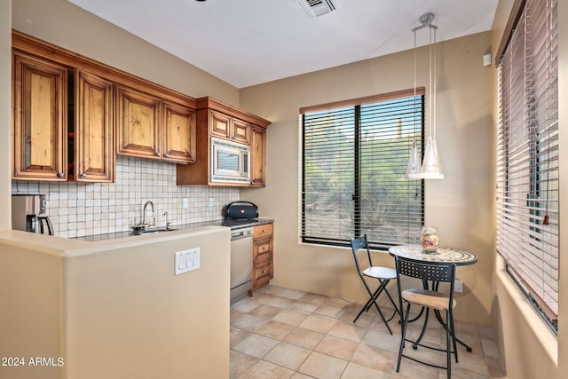 kitchen featuring decorative backsplash, appliances with stainless steel finishes, sink, light tile patterned floors, and pendant lighting