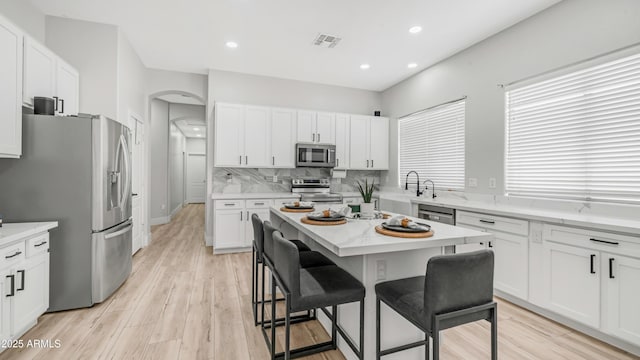 3103 S Benton, Mesa, AZ 85212 - kitchen featuring appliances with stainless steel finishes, a breakfast bar, arched walkways, white cabinets, and recessed lighting
