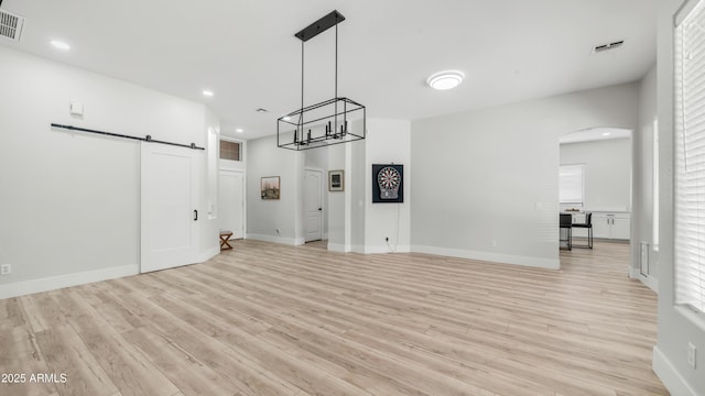 3103 S Benton, Mesa, AZ 85212 - unfurnished living room featuring a barn door, light wood-style flooring, arched walkways, recessed lighting, and baseboards