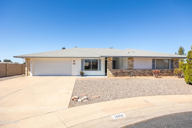 single story home featuring brick siding, roof with shingles, concrete driveway, an attached garage, and fence