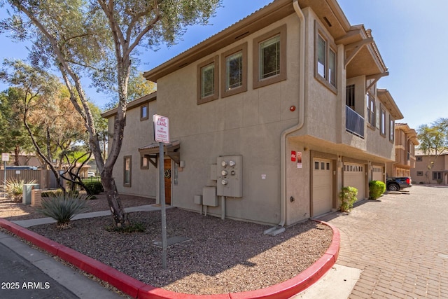 view of side of home with a garage, driveway, and stucco siding